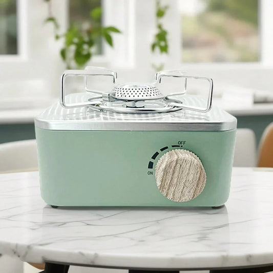 Mint green portable gas stove with wooden knob on marble kitchen table