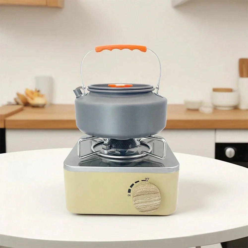 Portable gas stove with gray kettle and orange handle on white table in modern kitchen