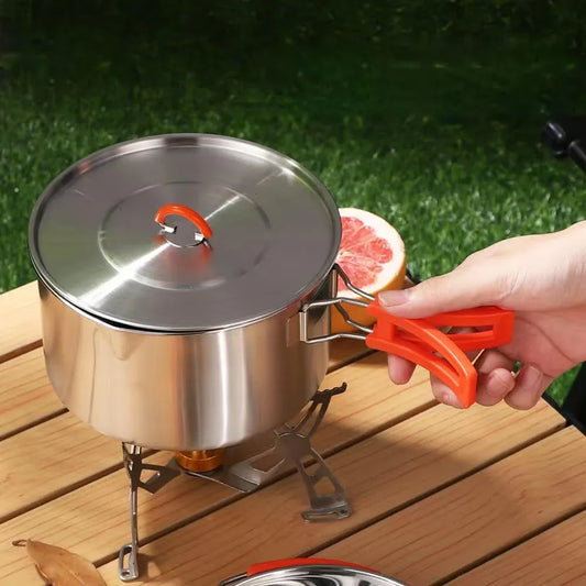 Stainless steel camping pot with orange handle on outdoor wooden table, Nightline Supply co.