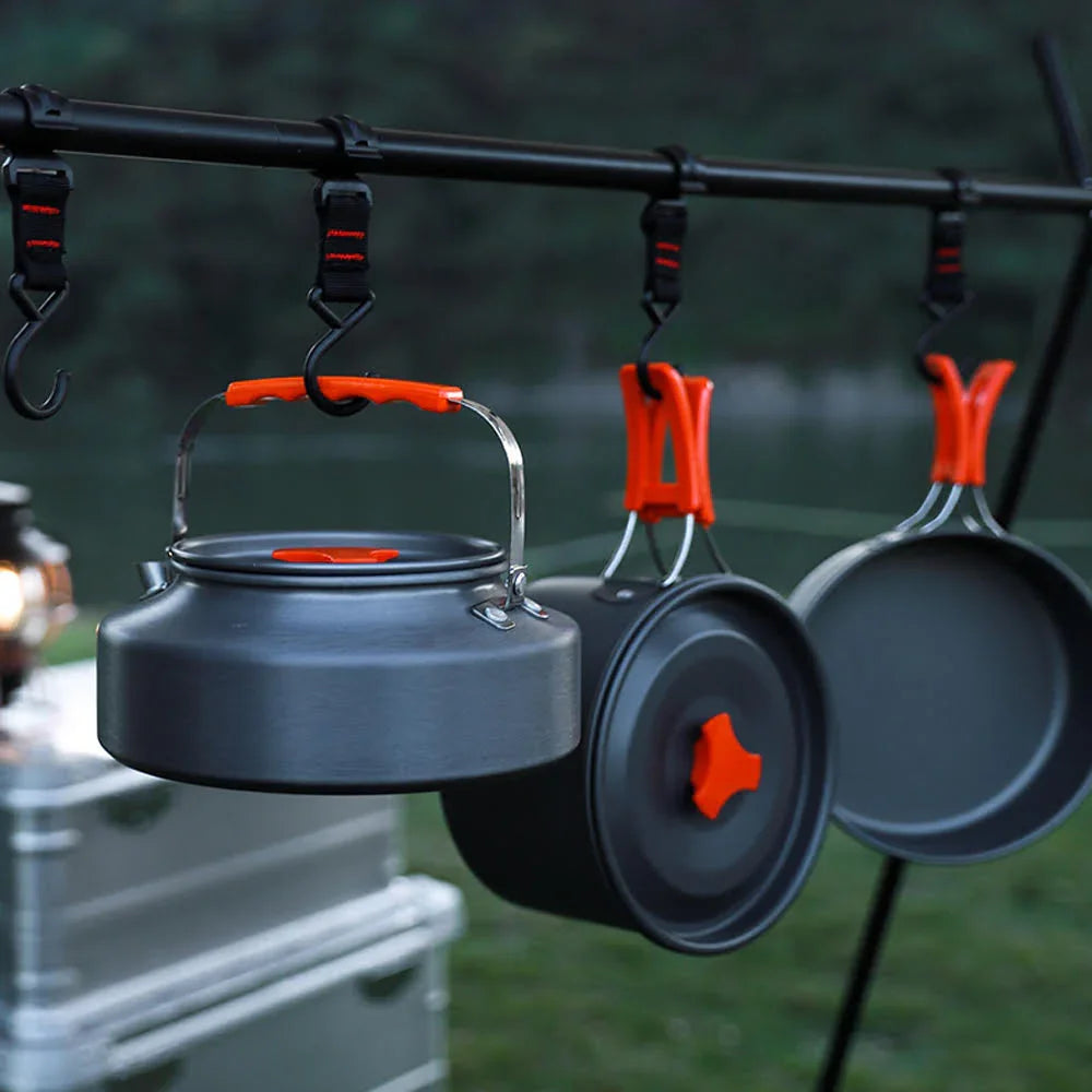 Camping cookware with orange handles hanging on hooks outdoors, Nightline Supply co.