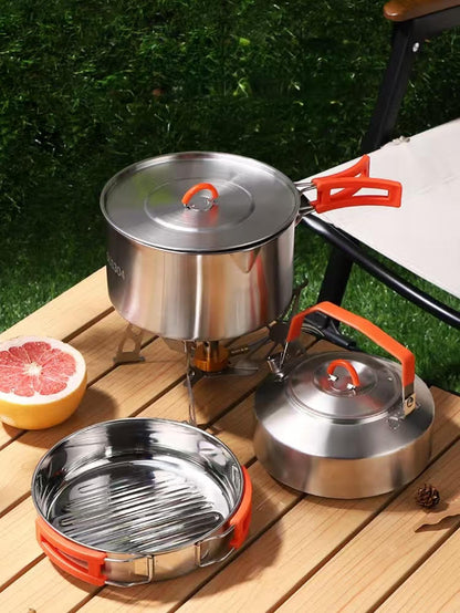 Outdoor cooking set with pots and a stove on a wooden surface.